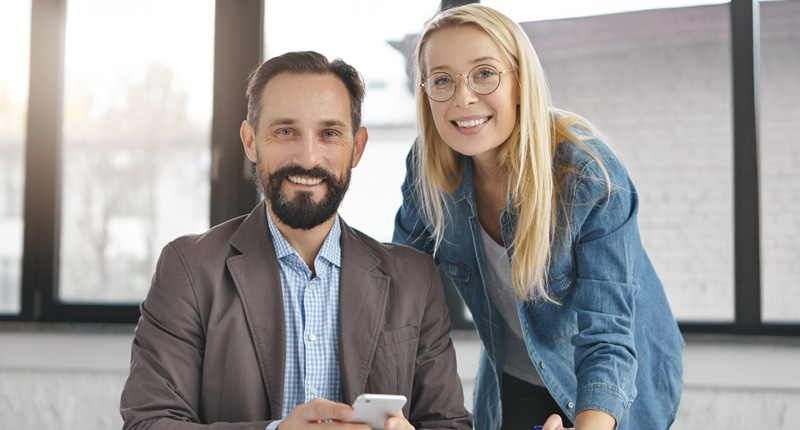 Man und Frau im Büro, lächeln in die Kamera