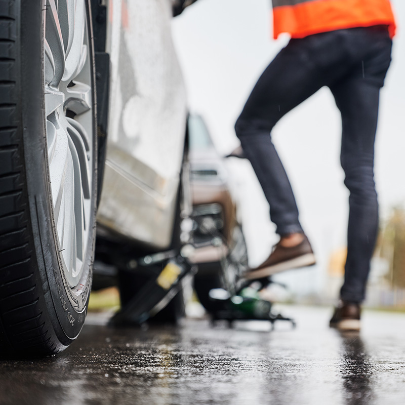 Reifenpanne, Person in Warnweste wechselt Reifen